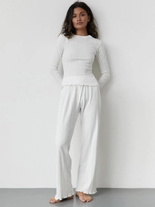Close-up of white rib-knit pajamas featuring elegant ruffle trim and soft fabric texture