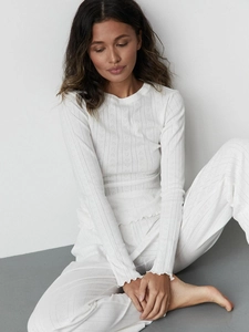 Detail of white long sleeve loungewear set featuring ribbed knit and ruffled edges