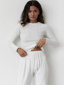 Close-up of white pointelle knit fabric with delicate heart patterns and lettuce edge hem