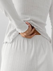 Detail of white knit loungewear with heart-shaped cutouts and delicate ruffled edges