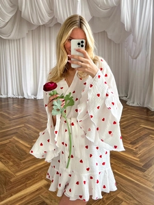 Detail of ruffled sleeves and red heart print on white muslin cotton bathrobe