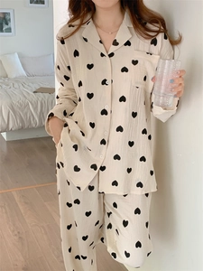 Detail of soft cotton pajama set featuring black heart print on cream fabric with buttons