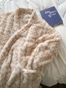 Detailed view of thick flannel bathrobe with brown pattern on white bedding background
