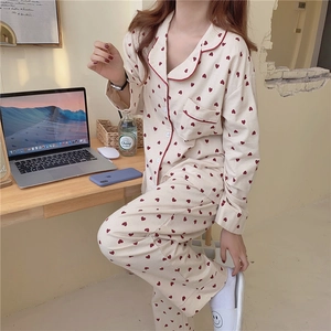 Detail of sweet heart pattern on beige long-sleeved pajamas with red piping