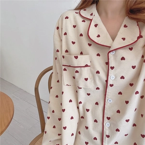 Close-up of cream pajamas with red heart prints, notched lapel and piped chest pocket