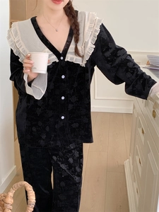 Détail d'un pyjama en velours noir avec col à volants blancs et texture fleurie