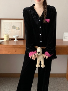Détail d'un pyjama en velours noir avec bordure en dentelle rose sur les manches et la poche