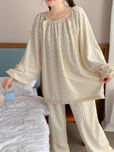 Dettaglio pigiama in maglia bianco crema con bordo a frange e trama a rilievo
