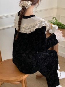 Détail du vêtement d'intérieur en velours noir avec relief fleuri et col à volants