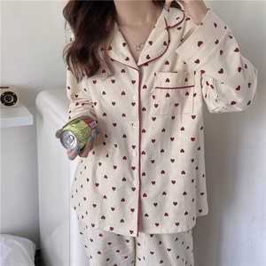 Detail of red heart prints on soft beige long-sleeve pajama set with contrast piping