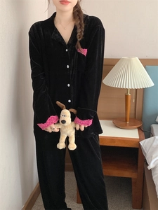 Détail de pyjama en velours noir avec bordure en dentelle rose sur manches et poche