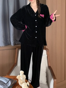Détail de pyjama en velours noir avec bordure en dentelle rose fuchsia aux poignets