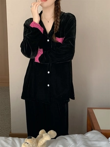 Détail d'un pyjama en velours noir avec dentelle rose et boutons blancs aux poignets