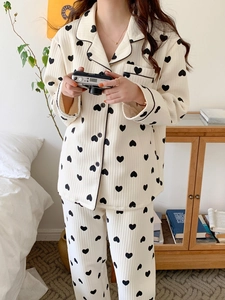 Detail of cream long-sleeved pajamas with black hearts and contrast piping trim