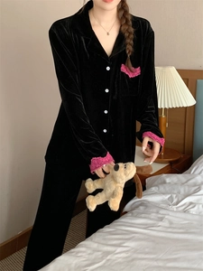 Détail du haut de pyjama en velours noir avec dentelle rose et boutons blancs en chambre