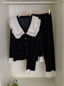 Détail de pyjama en velours noir avec motif floral rétro et grand col blanc à volants