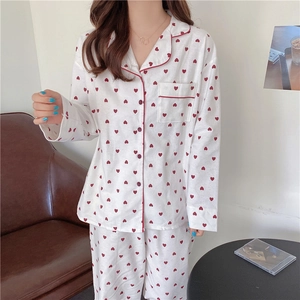 Close-up of red heart print pajamas featuring red piping and a chest pocket detail