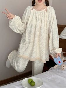 Dettaglio del pigiama bianco crema con trama jacquard a V e nappe raffinate sull'orlo