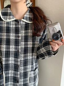 Detail of checkered pajama top with Peter Pan collar and white piping trim