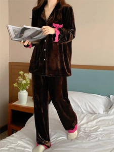 Détail de pyjama en velours marron foncé avec bordure en dentelle rose sur les poches