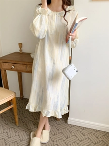 Detail of sweet long-sleeve cotton nightgown with ruffle collar and light yellow texture