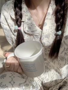 Détail du col de pyjama à fleurs avec collier cœur et bague dorée élégante