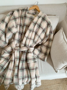 Close-up of pink and green plaid fleece bathrobe texture and waist tie on sofa