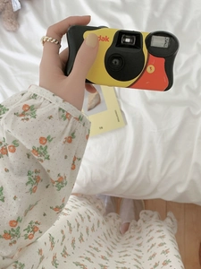 Detail of vintage disposable camera held by a model in a floral cotton nightgown