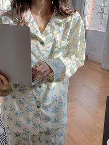 Detail of floral cotton pajama set with green plaid piping and round buttons in a cozy setting