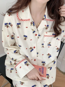 Détail d'un haut de pyjama en coton doux avec oursons et finitions à carreaux rouges