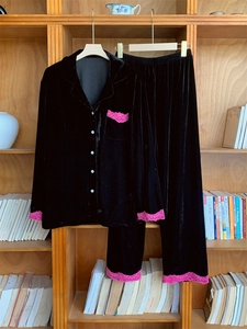 Détail de pyjama en velours noir avec dentelle rose et boutons sur étagère bois