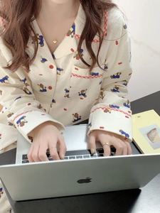 Détail du pyjama en coton crème avec imprimé ours et bordures à carreaux rouges