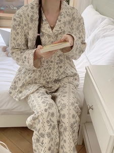 Détail d'un pyjama en coton à fleurs avec manches longues et boutons dans une chambre