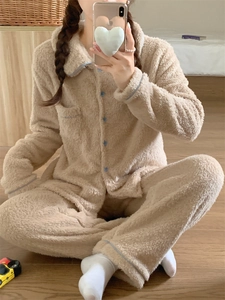Detailed close-up of thick beige coral fleece pajamas with blue buttons and contrast piping