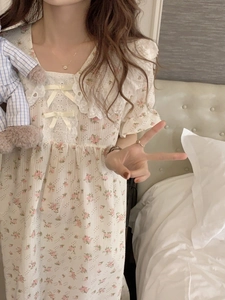 Dettaglio di camicia da notte a fiori con colletto in pizzo e fiocchi gialli