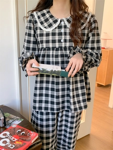 Detail eines schwarz-weißen Gingham-Pyjama-Sets mit großem weißem Spitzen-Peter-Pan-Kragen