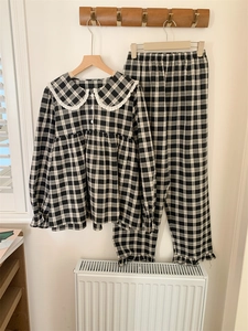 Detail eines karierten Pyjama-Sets mit Peter-Pan-Kragen und feiner weißer Spitze