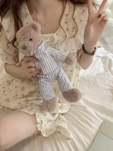 Dettaglio di camicia da notte a fiori con colletto in pizzo e orsetto di peluche