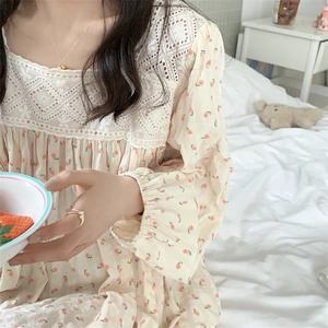 Dettaglio del colletto in pizzo bianco e motivo floreale sulla camicia da notte crema