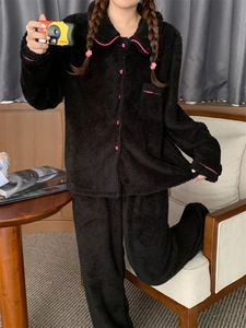 Detail of black fleece pajama set featuring pink contrast piping and soft fluffy texture