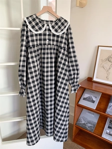 Detail eines karierten Hauskleides mit weißem Spitzenkragen und Rüschenärmeln