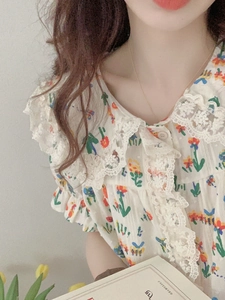 Détail du haut de pyjama à fleurs avec bordure en dentelle blanche et col Peter Pan