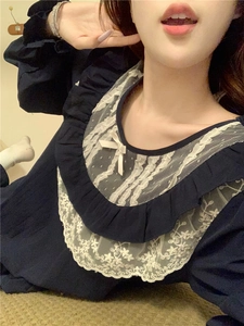 Close-up of navy blue pajamas with white floral lace neckline and silk bow detail
