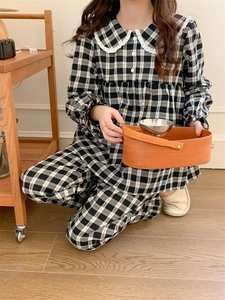 Detail des karierten Pyjama-Sets mit weißem Spitzen-Puppenkragen und Knopfverschluss