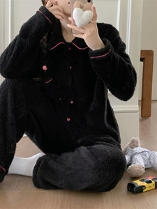 Detail of pink heart buttons and piping on a black fleece pajama set for women