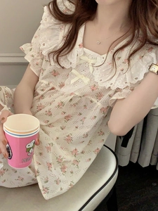 Dettaglio di camicia da notte a fiori con scollo a balze, ricamo e fiocchi di raso