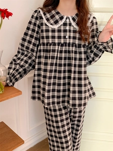 Detail eines schwarz-weißen Karo-Pyjamas mit Spitzenkragen und weißen Knöpfen