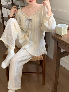 Detail of ruffle trim and purple ribbon bow on striped loungewear with pleated texture