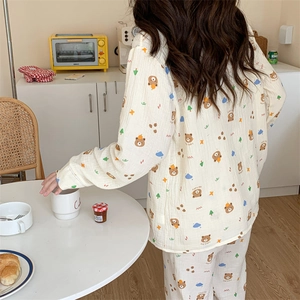 Detail of soft cream cotton pajamas featuring cute brown bear and pine tree patterns