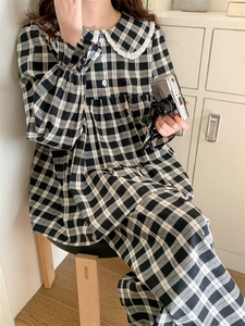 Detail von schwarz-weißem kariertem Pyjama-Set mit Spitzenkragen und weißen Knöpfen